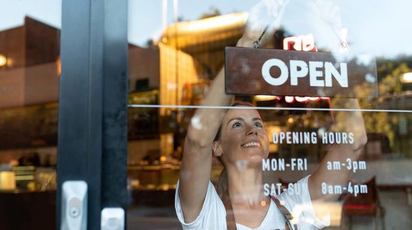 Woman hanging open sign in business