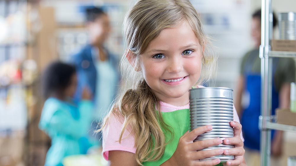 Little girl holding canned food goods