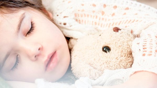 A child sleeping with a teddy bear