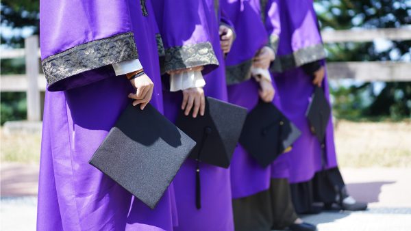 students in graduation gowns holding caps