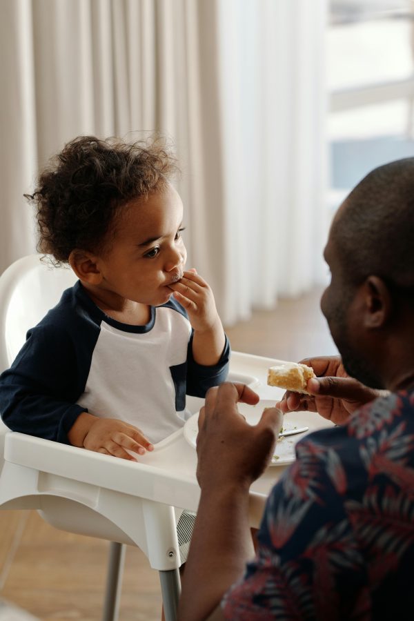 Father feeding child in a highchair